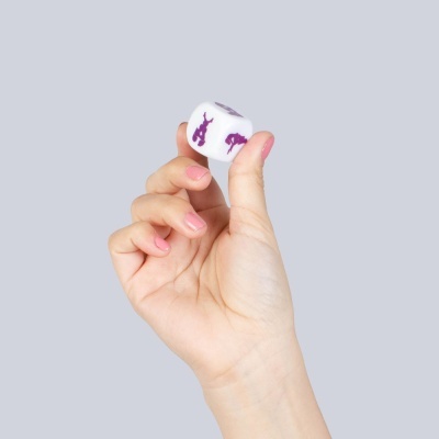 Mão segurando um dado branco com figuras roxas