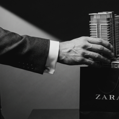 Fotografia conceptual em preto e branco: mão de um homem de negócios a tirar uma maquete de arranha-