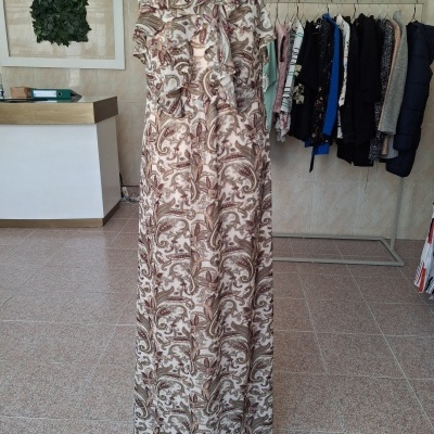 Vestido comprido com padrão paisley castanho e bege em manequim branco dentro de loja