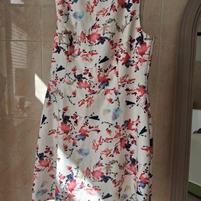 Vestido branco com padrão floral colorido pendurado num cabide