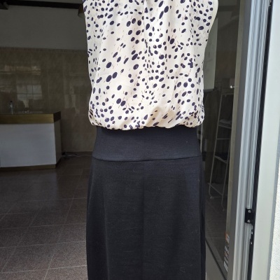 Vestido com padrão de manchas negras na parte superior creme e saia preta em manequim