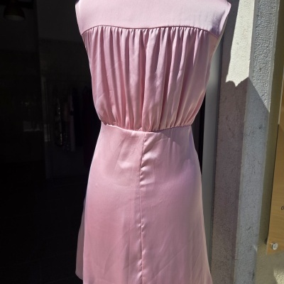 Vestido rosa acetinado e sem mangas visto de costas em manequim