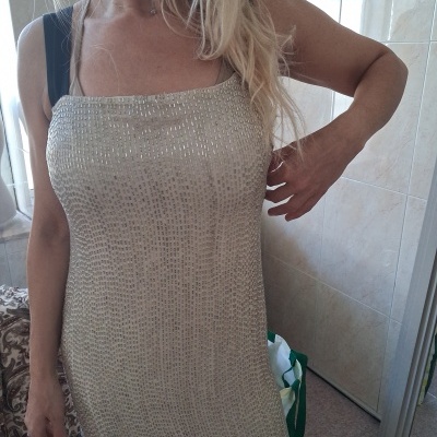 Vestido sem mangas bege com textura metálica e padrões em relevo, em ambiente interior