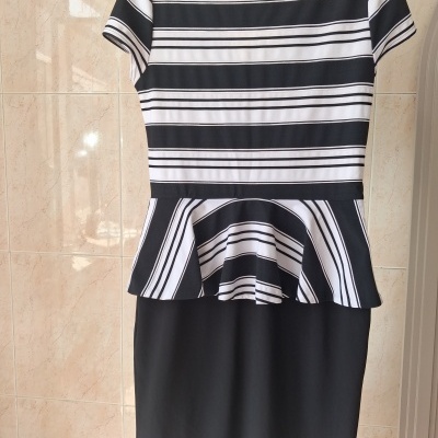 Vestido preto com parte superior às riscas brancas e pretas, manga curta, pendurado na parede