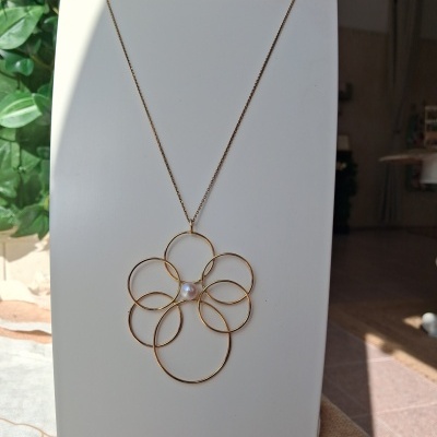 Colar dourado com pendente em forma de flor e pérola no centro