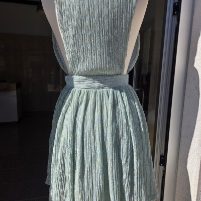 Vestido azul claro metálico com tecido plissado no manequim