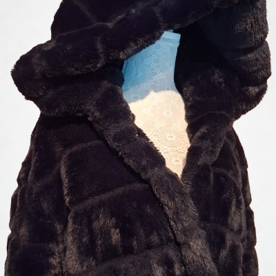 Casaco preto de pêlo sintético com capuz em manequim branco