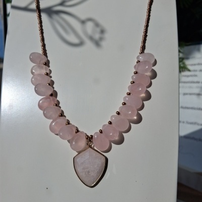 Colar com pedras de quartzo rosa e pendente em forma de escudo num suporte branco