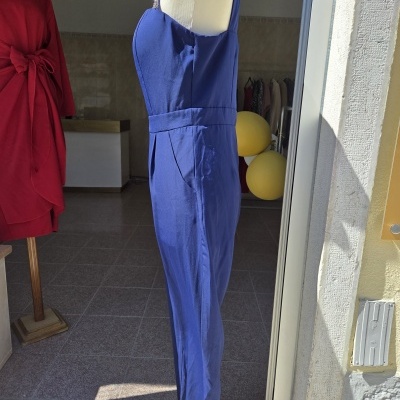 Macacão azul com alças finas em manequim dentro de loja próximo a porta aberta