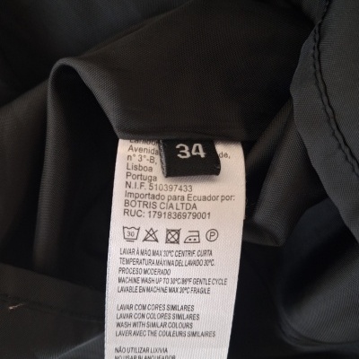 Etiqueta de roupa com tamanho 34 e instruções de lavagem em tecido preto