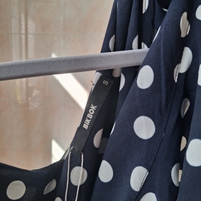 Roupa azul com bolas brancas pendurada em cabide cinzento com etiqueta BIKE BOK S