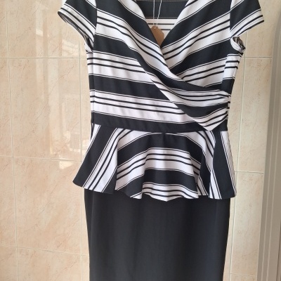 Vestido preto com parte superior de riscas preto e branco em padrão horizontal, gola em V, mangas curtas e folho na cintura