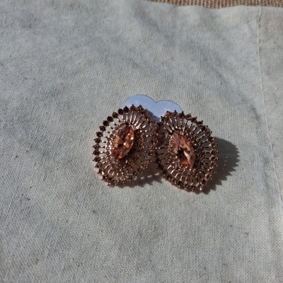 Brincos de argola dourados com pedra âmbar sobre tecido branco