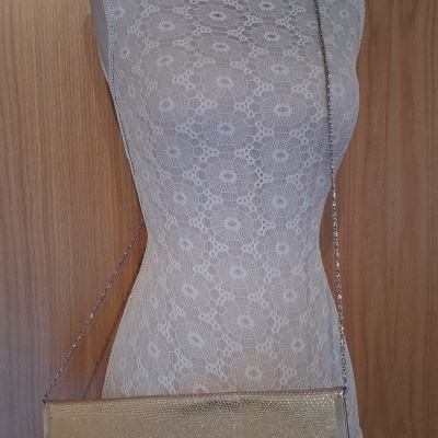Bolsa de festa dourada com textura de pele de réptil e alça de corrente prateada