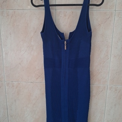 Vestido justo azul escuro com fecho frontal pendurado num cabide preto
