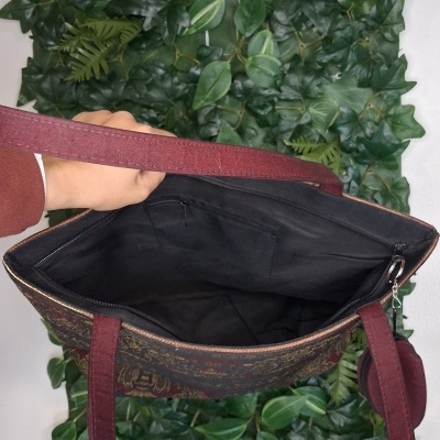 Mala de tecido floral com alças vermelhas e interior preto aberta