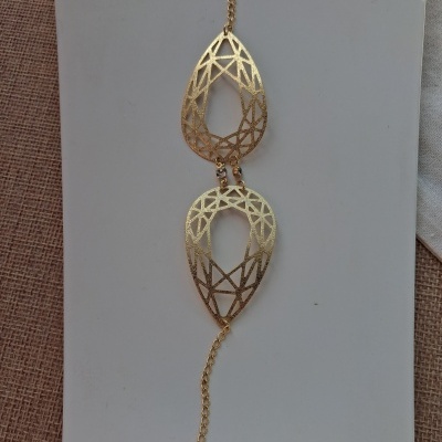 Pulseira dourada com dois pendentes em padrão geométrico e corrente.