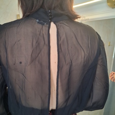 Blusa preta transparente e saia com lantejoulas vermelhas e castanhas vista de costas
