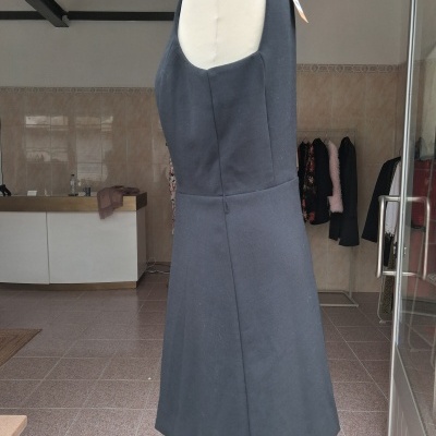 Vestido cinzento escuro sem mangas num manequim em interior com chão e paredes revestidas.