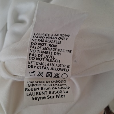 Etiqueta de cuidados de roupa branca com instruções de lavagem e secagem.