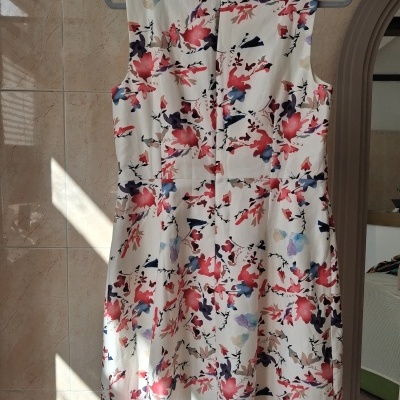 Vestido floral branco com padrão colorido pendurado numa cabide