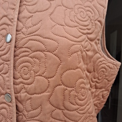 Colete acolchoado cor de rosa com padrão floral e botões metálicos prateados