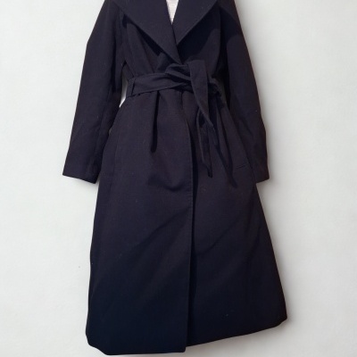 Casaco comprido preto com cinto num manequim