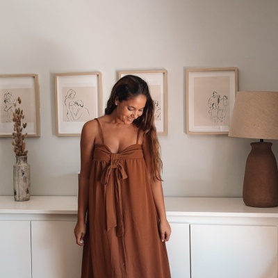 Vestido longo castanho com alças e laço frontal em ambiente interior