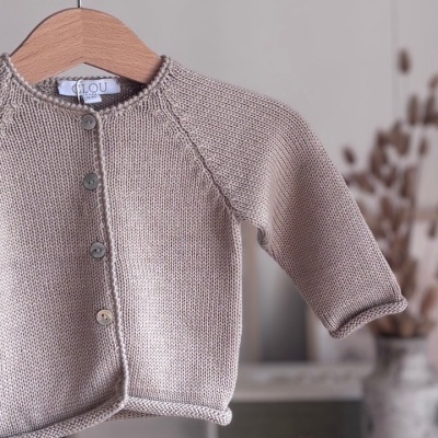 Casaco infantil bege em malha pendurado