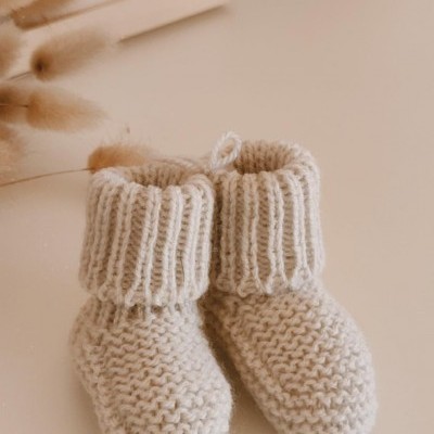Botas de bebé em lã branca com textura de malha grossa e punhos canelados.