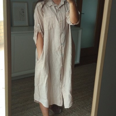 Vestido comprido bege com botões e bolsos, sandálias castanhas claras em ambiente interno