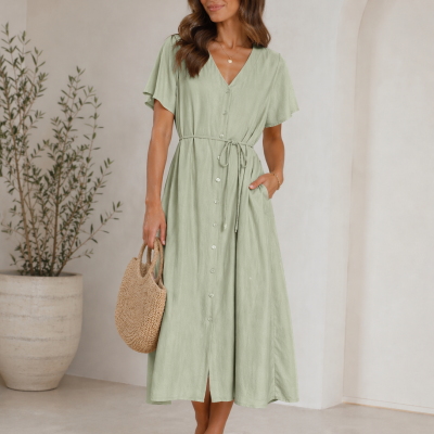 Vestido midi verde claro com botões e cinto fino, mala de palha e sandálias bege