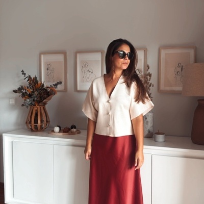 Mulher com blusa branca e saia vermelha numa sala com decoração minimalista.