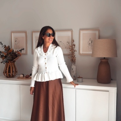 Mulher com camisola branca e saia castanha numa sala moderna