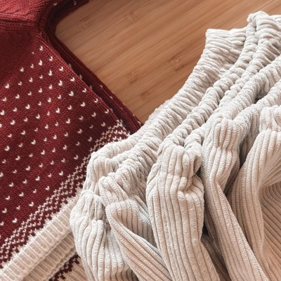 Roupas de malha vermelha e tecido canelado bege sobre superfície de madeira