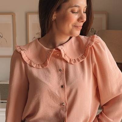 Blusa feminina rosa com gola babada e botões, usada com calças brancas