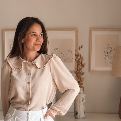 Camisa feminina creme com folhos e botões, calças brancas, ambiente interior minimalista