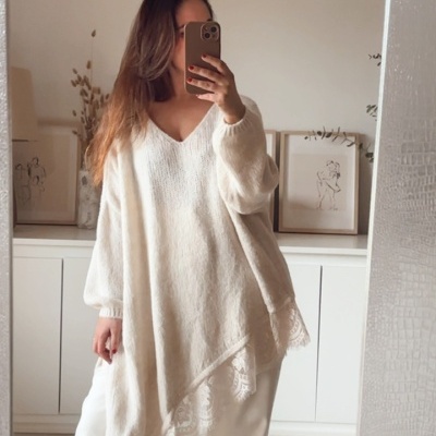 Mulher com camisola branca oversize e calças em frente a espelho num ambiente interior