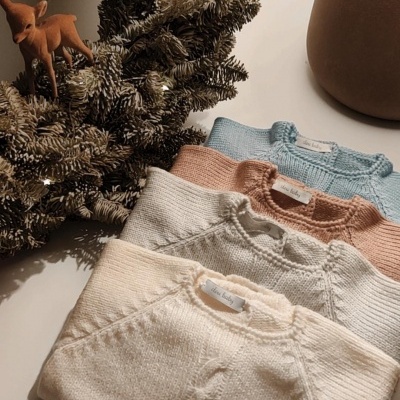 Camisolas de malha dobradas e decoração natalícia com luzes e veado.