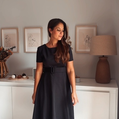 Vestido comprido preto com cinto largo usado por mulher em ambiente interior minimalista