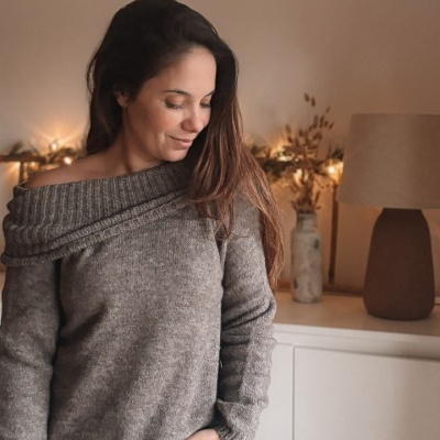 Mulher com camisola de malha cinzenta e calças de ganga azuis em ambiente interior