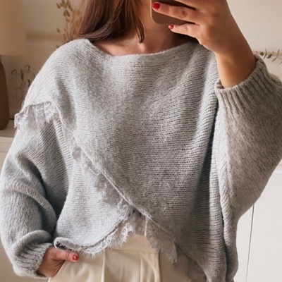 Pessoa a usar pullover cinzento claro de malha grossa com renda e calças claras num ambiente interior