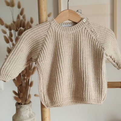 Camisola de malha bege de bebé pendurada num cabide