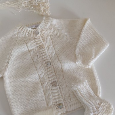 Conjunto de bebé em malha branca com camisola e meias, com padrões em trança e botões nacarados