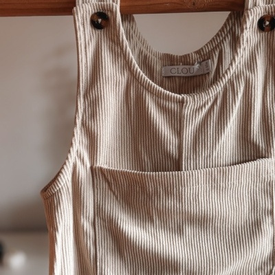 Macacão de algodão riscado branco e bege com botões pretos pendurado