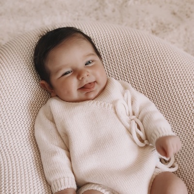Bebé em macacão creme em puff redondo de malha
