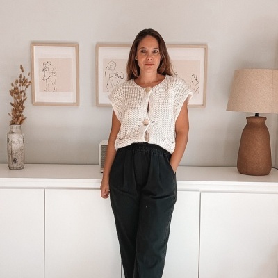 Mulher vestindo colete branco e calças pretas em ambiente interior minimalista