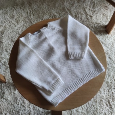 Camisola branca de malha em mesa redonda de madeira