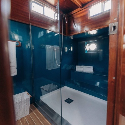 Cabine de duche azul com teto de madeira e toalhas com texto papadouro