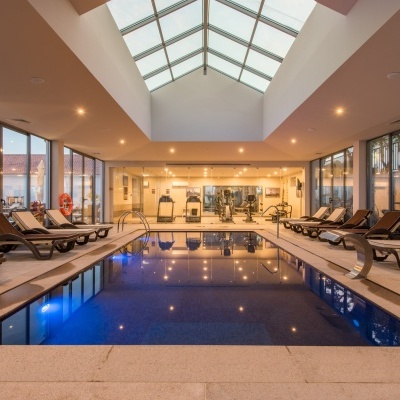 Piscina interior com espreguiçadeiras e ginásio ao fundo